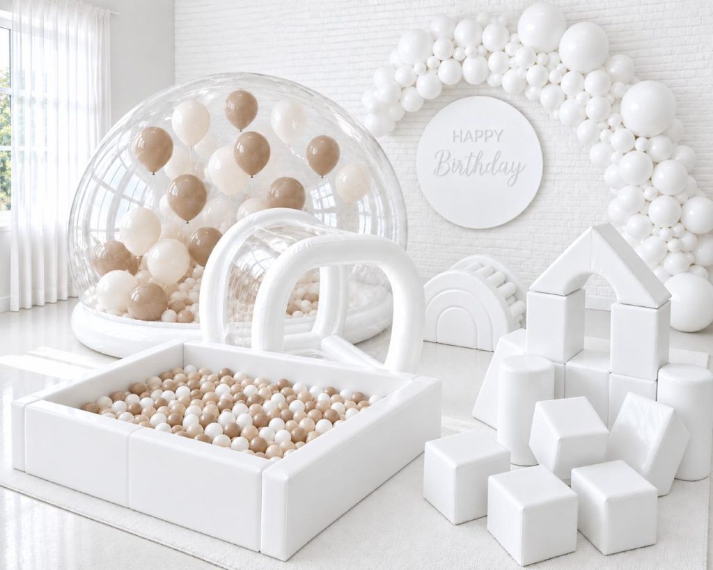 White bubble bounce with balloons beside an all-white soft play setup