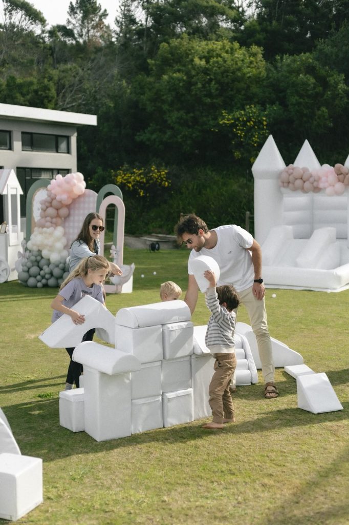 Family building a wall with white soft play blocks, with the white jumping castle behind