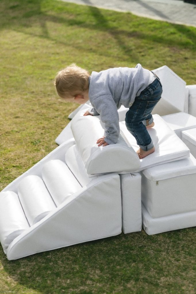 Toddler climbing over the white soft play steps and blocks